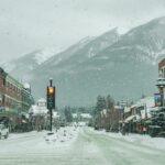 Snow-covered street in Banff, Alberta with mountain backdrop and stoplights #MoraineLakeShuttle #LakeLouiseTour #BanffExplorer #ExploreBanff #MoraineLakeAccess